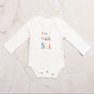 Baby Long Sleeve Graphic Organic Bodysuit in Crawl Walk Ski on a marble table at Addison West