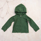 Organic Hoodie in Basil Green on a marble table at Addison West