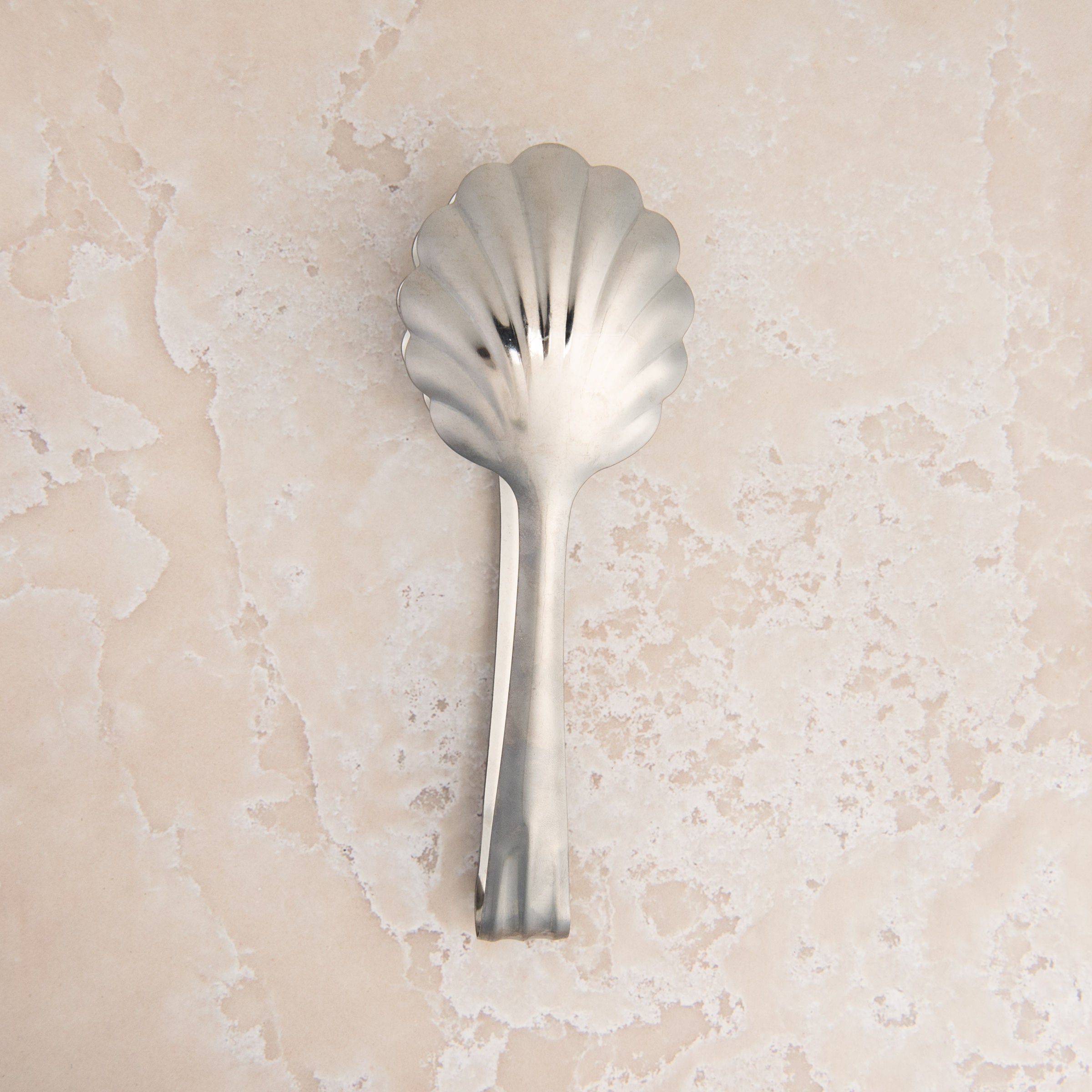 Scalloped Serving Tongs on a beige background at Addison West
