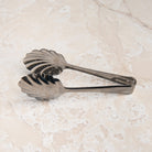 Scalloped Serving Tongs on a beige background at Addison West