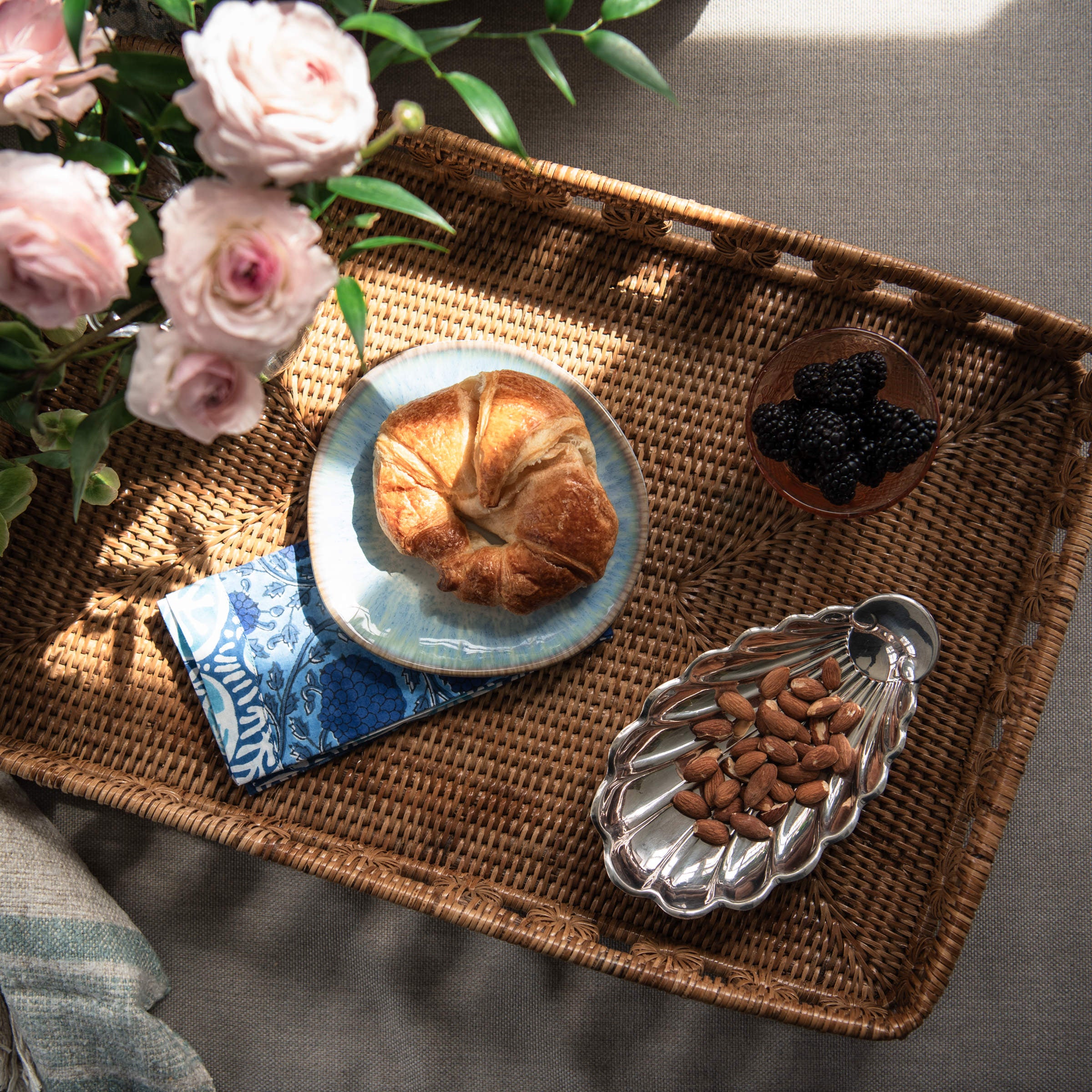 Vermont Handmade Napkins in Sea Sky Blue, Organic Stoneware Plate, Vintage French Silver Shell Tray on a rattan tray from above at Addison West