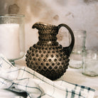 Hobnail Glass Pitcher in Smoky Amaro on a table at Addison West