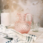 Hobnail Glass Pitcher in Petal Pink on a table at Addison West