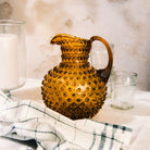 Hobnail Glass Pitcher in Saffron Light on a table at Addison West