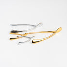 Gold and Silver Wishbone sulptures on a white background at Addison West