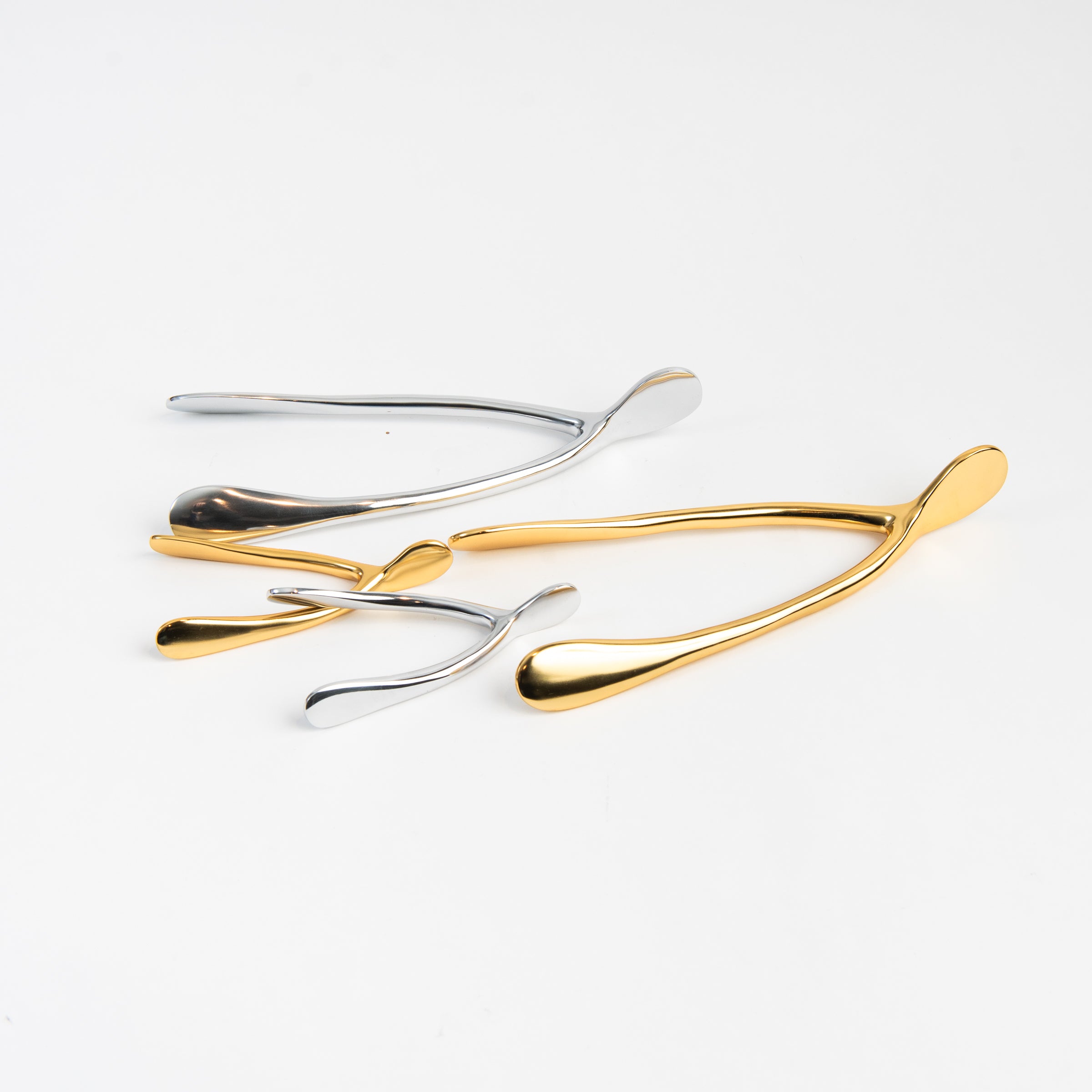 Gold and Silver Wishbone sulptures on a white background at Addison West