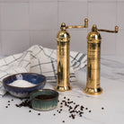 Alexander 8" Brass Pepper Mill and pepper mill on a white kitchen counter at Addison West