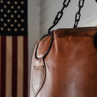 Pugilist Bag vintage punching bag in a room with ship lap walls and and American flag in the background