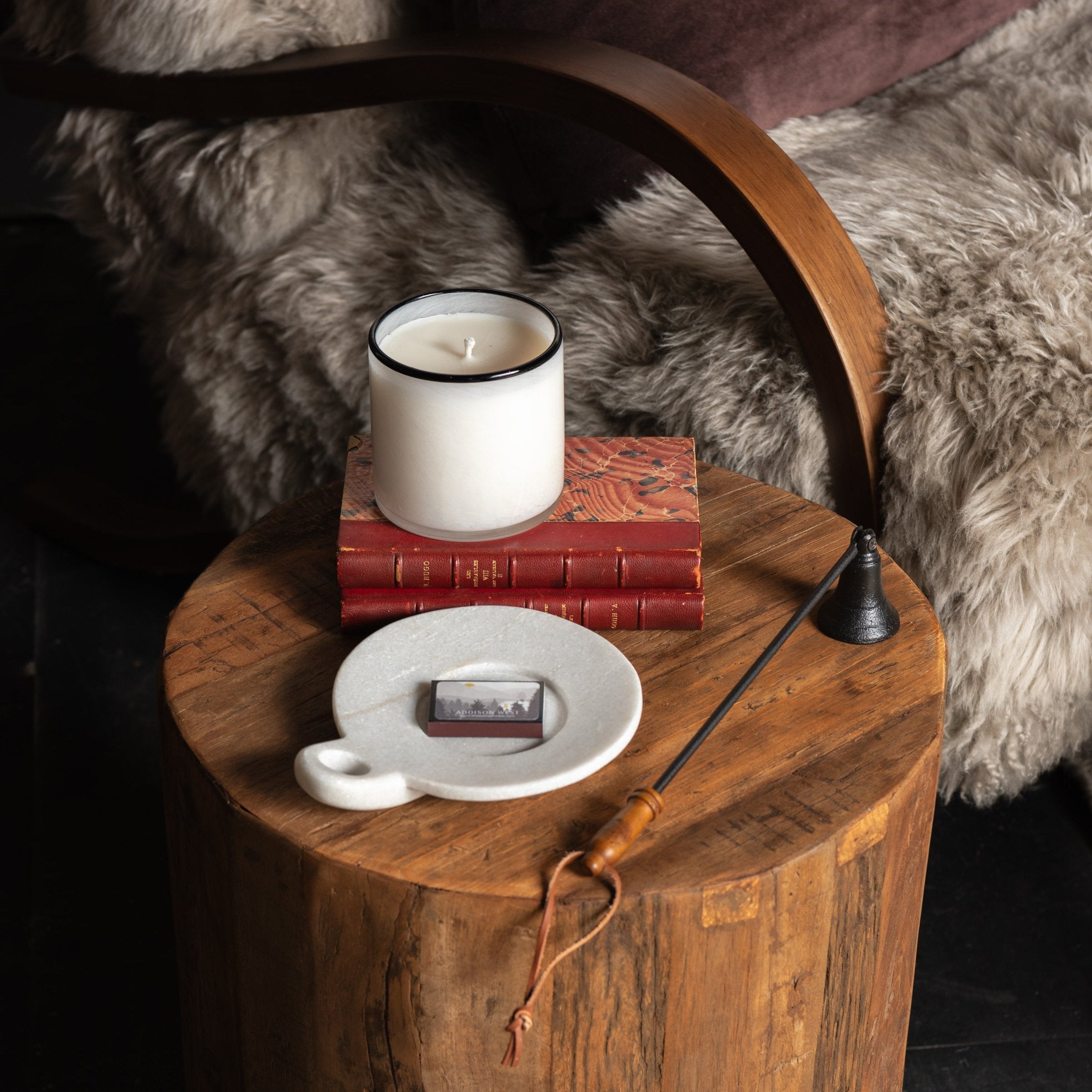 Lafco Champagne Signature Candle on an end table next to a furry arm chair