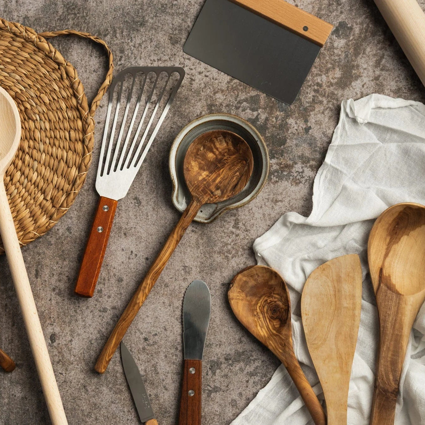 Collection of wooden kitchen utensils on a textured surface in Addison West Kitchen Tools & Utensils collection.