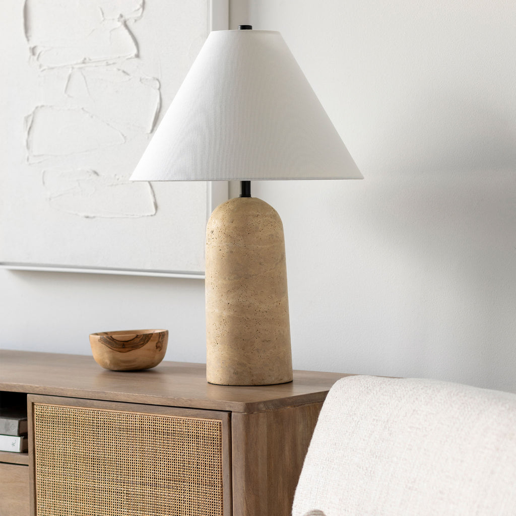 Surya brand Agate table lamp in natural travertose with white linen shade on a wood console with cane doors