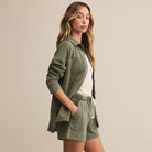 Woman wearing a green shirt and shorts on a beige background