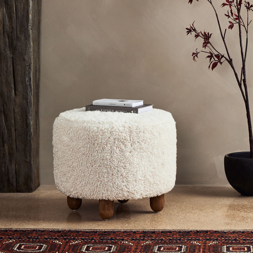 Four hands brand Aniston ottoman in natural shearling style upholstery in a room with an antique rug