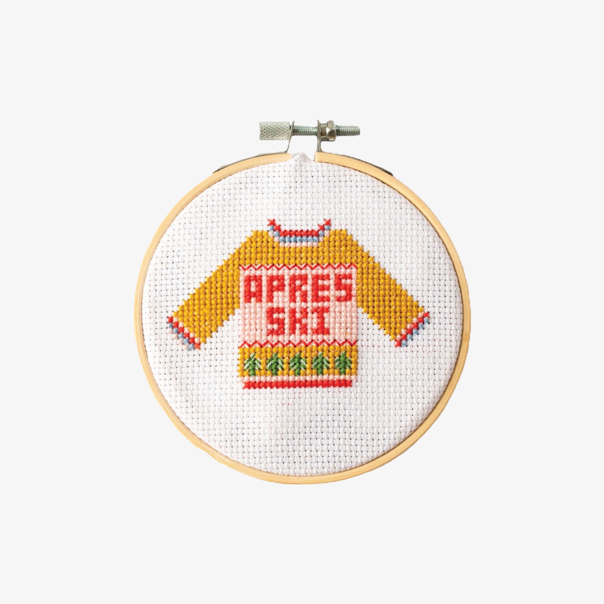 Cross-stitched design of a sweater with 'APRES SKI' text in a wooden hoop on a white background