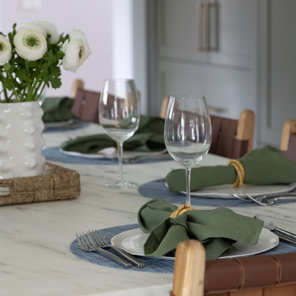 Marble top Table set with blue chilewhich placemats and green napkins and wine glasses