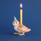 Owl-shaped candle holder with a lit candle on a blue background