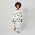 Child wearing a white onesie with Christmas-themed pattern on a plain background