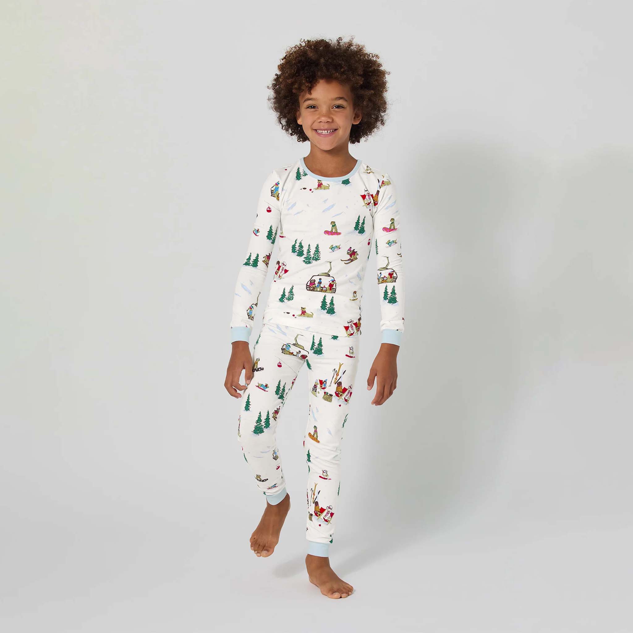 Child wearing a white onesie with Christmas-themed pattern on a plain background