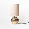 Creative coop antique brass finish table lamp with etched pattern and Linen Shade on a white background