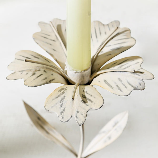 White metal candle holder with floral petals and leaves on a white background
