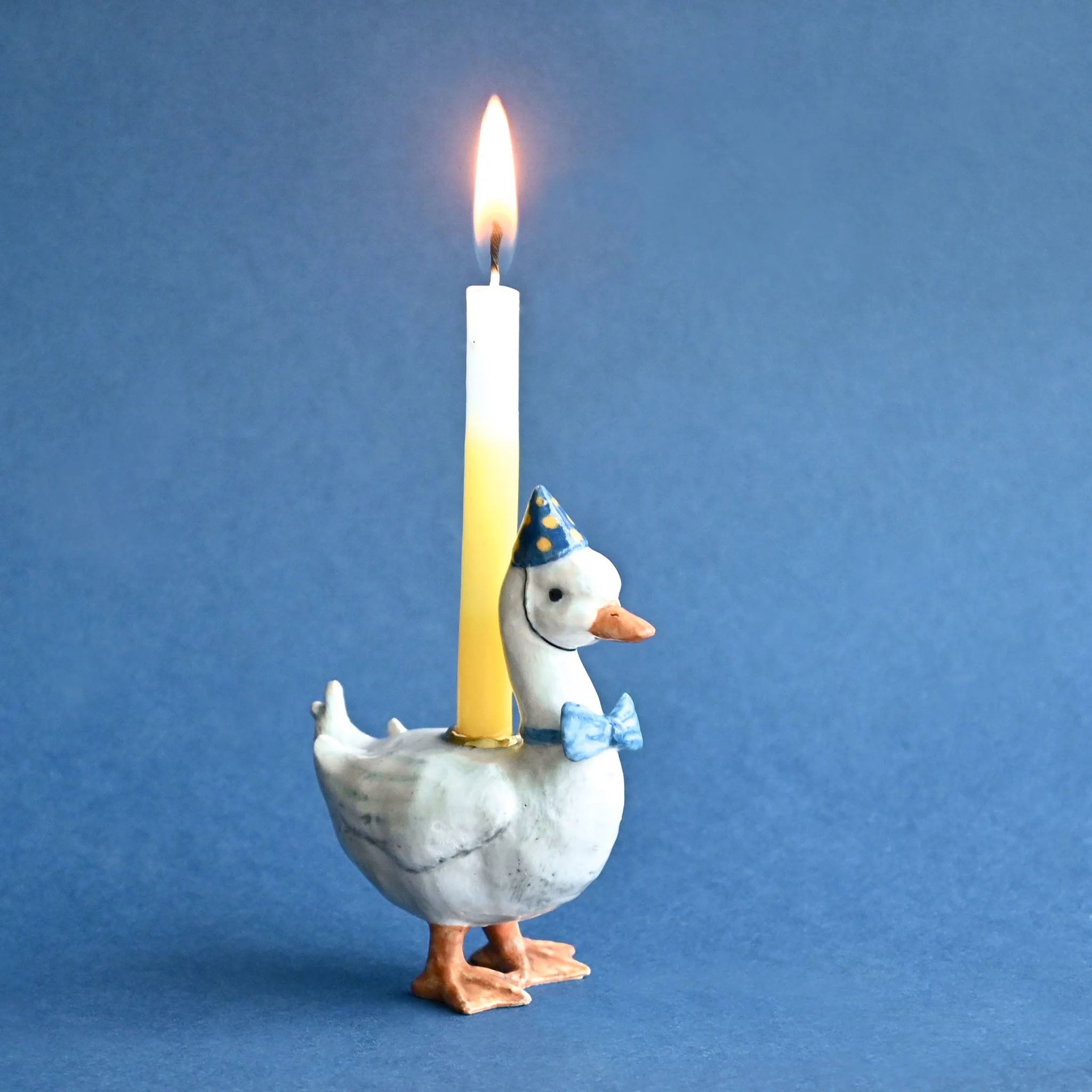 Decorative duck candle holder with a lit candle on a blue background