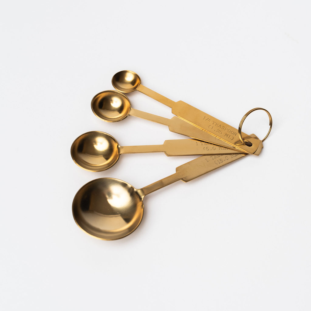 Set of four brass measuring spoons on a white backgrund