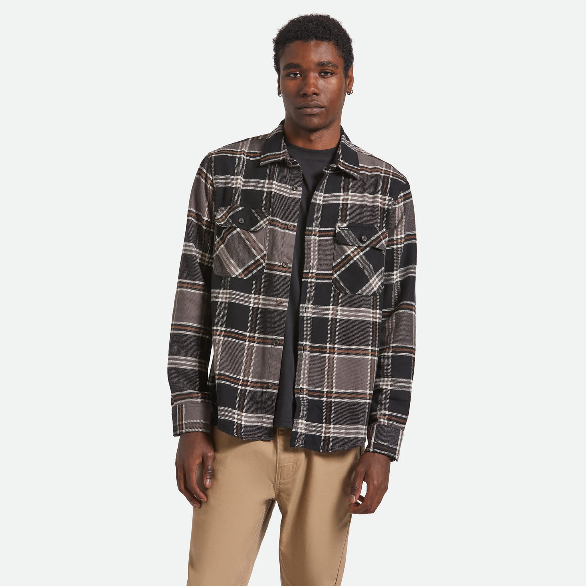 Man wearing a plaid shirt and beige pants on a white background