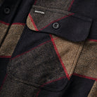 Close up of button up flannel shirt with black, red, grey, and beige plaid and grey buttons.