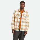 Man wearing a plaid shirt over an orange sweater on a white background
