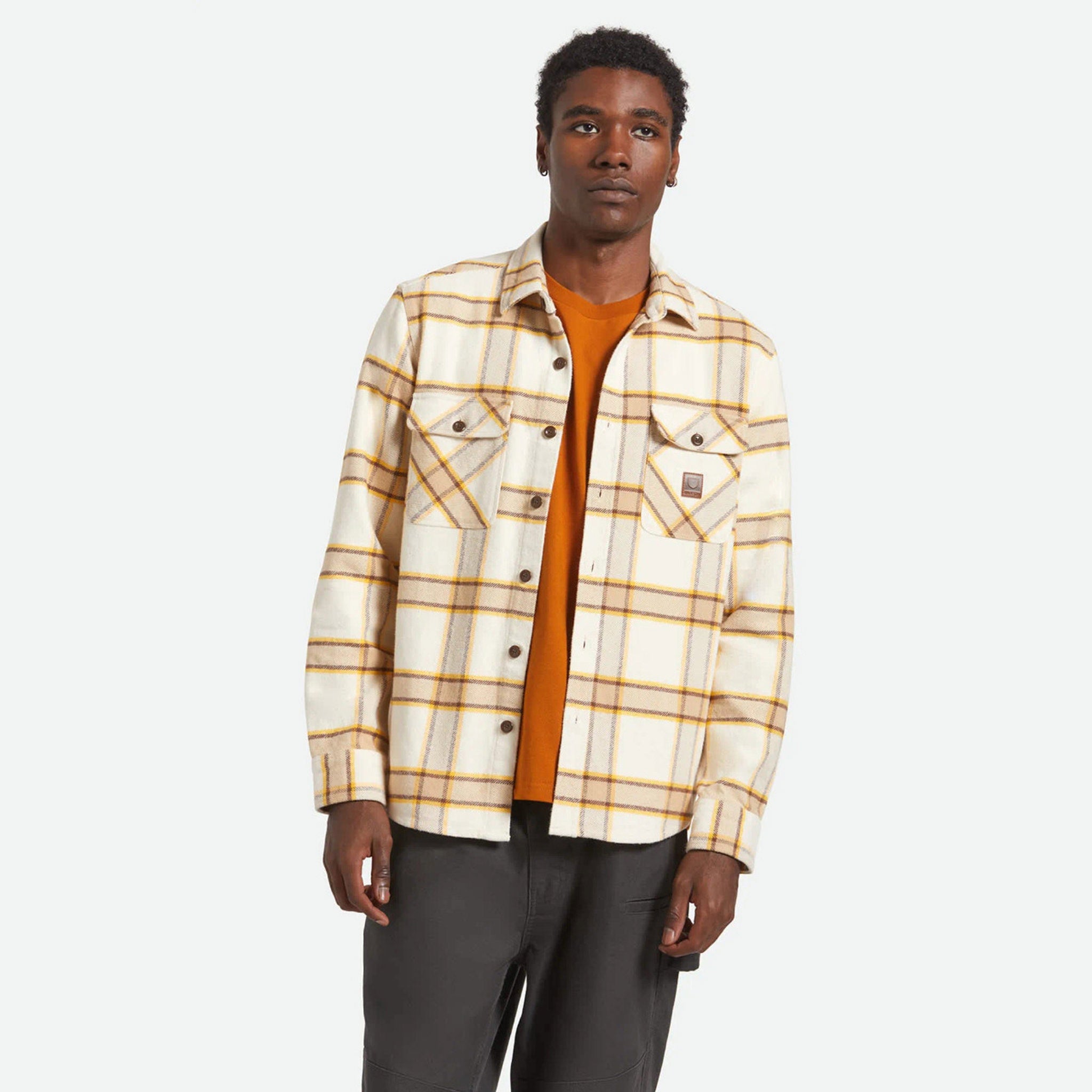 Man wearing a plaid shirt over an orange sweater on a white background