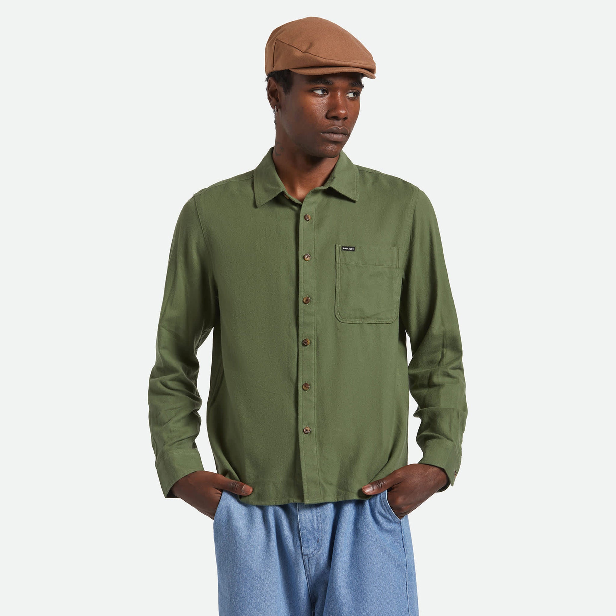 Man wearing a green shirt and brown cap on a white background