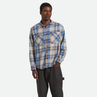 Man wearing a plaid shirt and dark pants on a white background