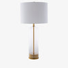 Glass table lamp with white shade and brass base and accents on a white background