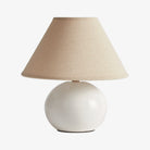 Table lamp with beige lampshade and white base on a white background
