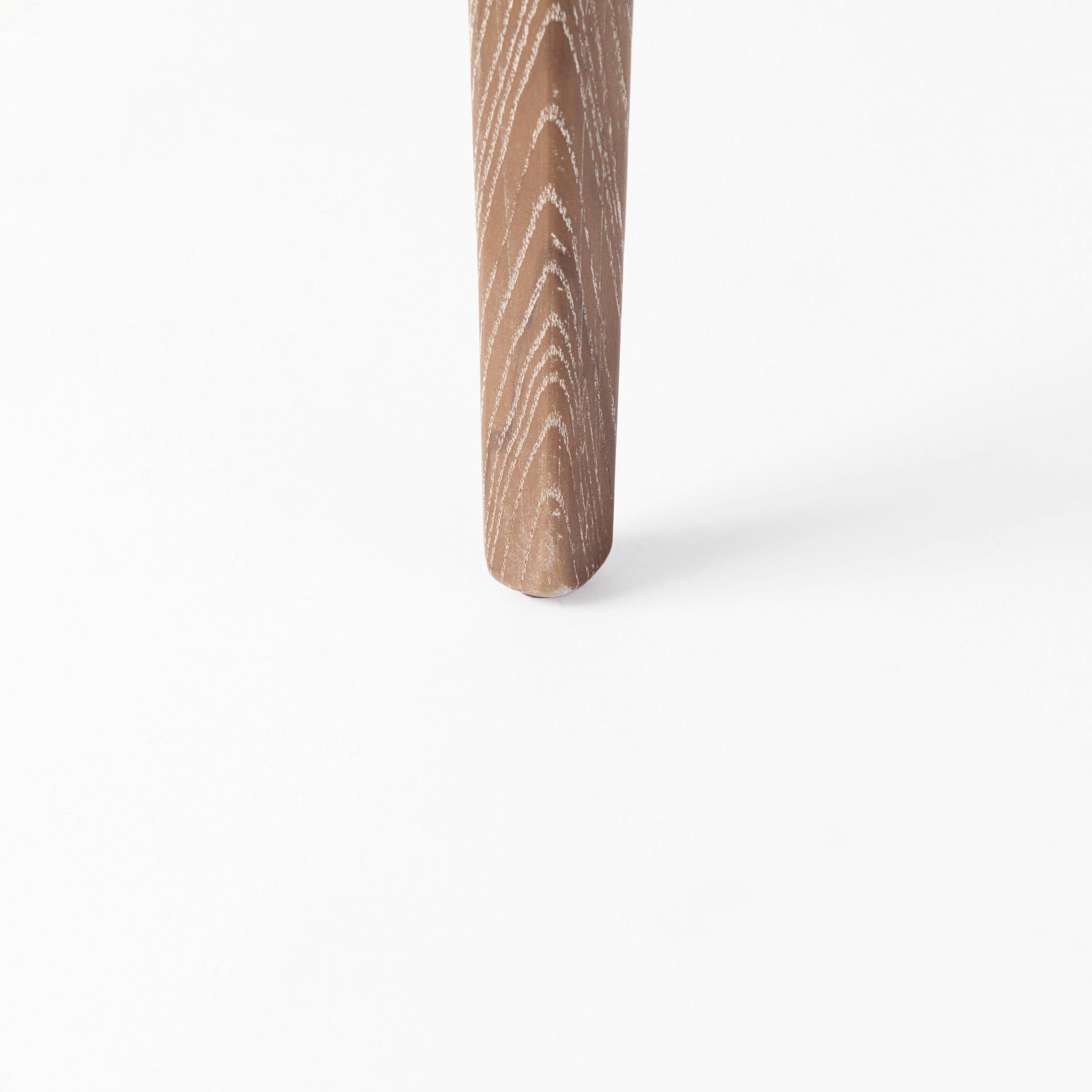 Close up of leg of Clara Light Brown Wood W/ Cream Fabric Seat and Cane Back Dining Chair on a white background
