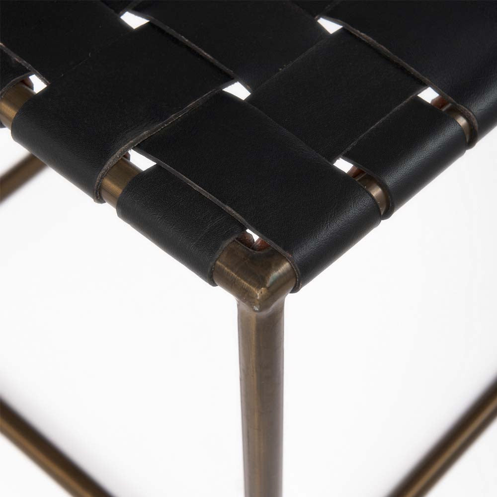 Close up of Black Leather Woven Seat with Gold Metal Frame Stool on a white background
