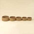 Five woven baskets of varying sizes on a beige background
