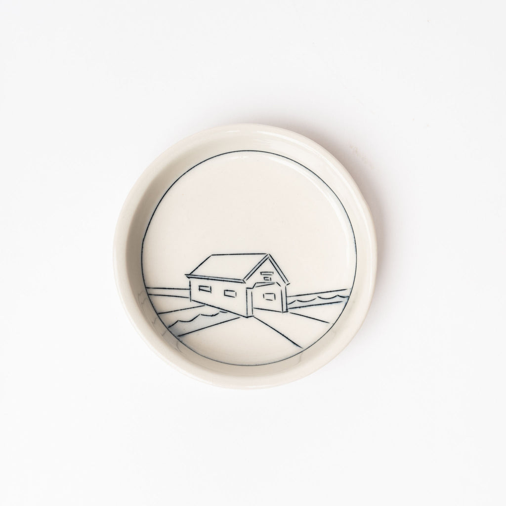 Small white handmade dish with drawing of covered bridge on a white background