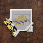 Butter Needlepoint Kit on a wood table at Addison West