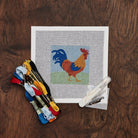 Rooster Needlepoint Kit on a wood table at Addison West