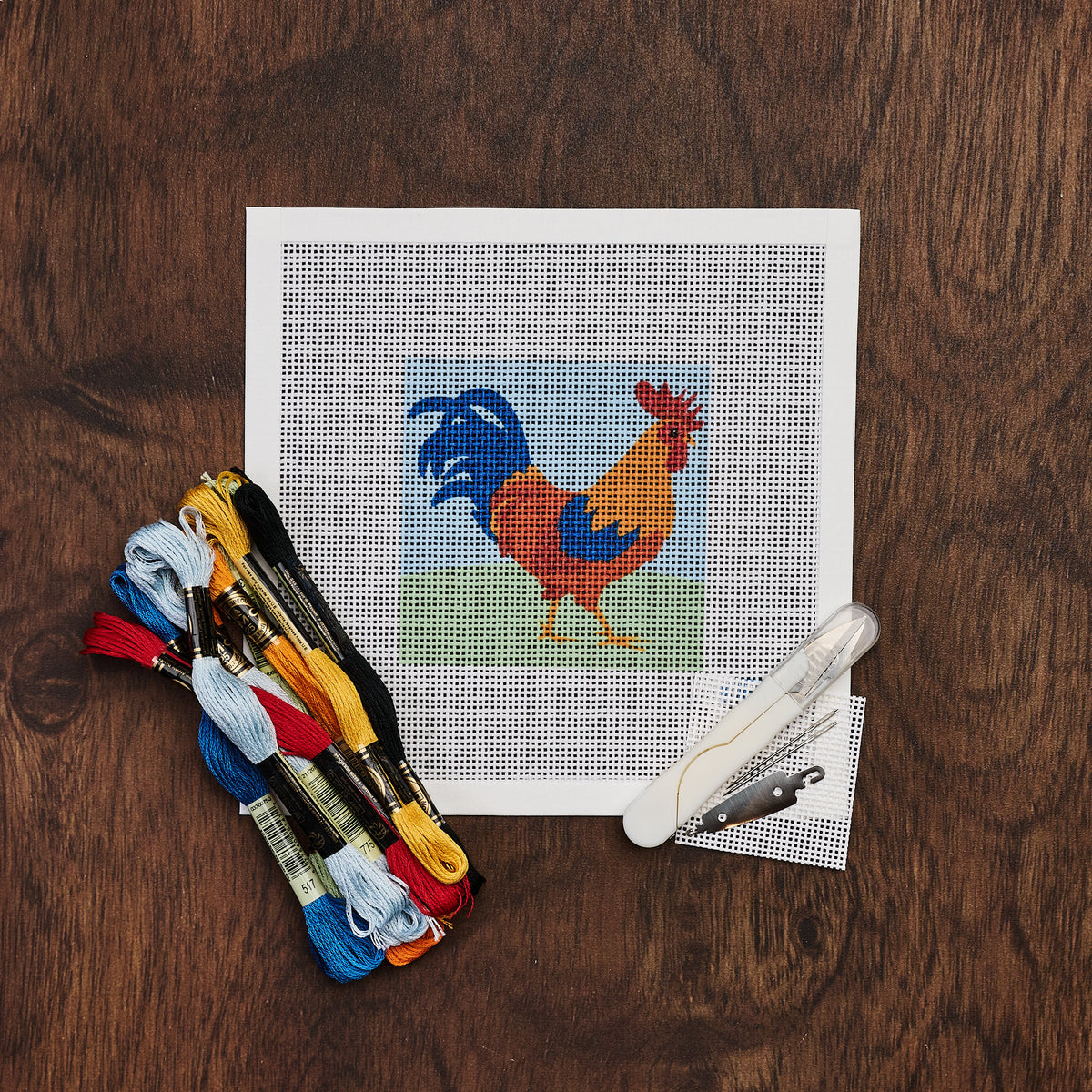 Rooster Needlepoint Kit on a wood table at Addison West