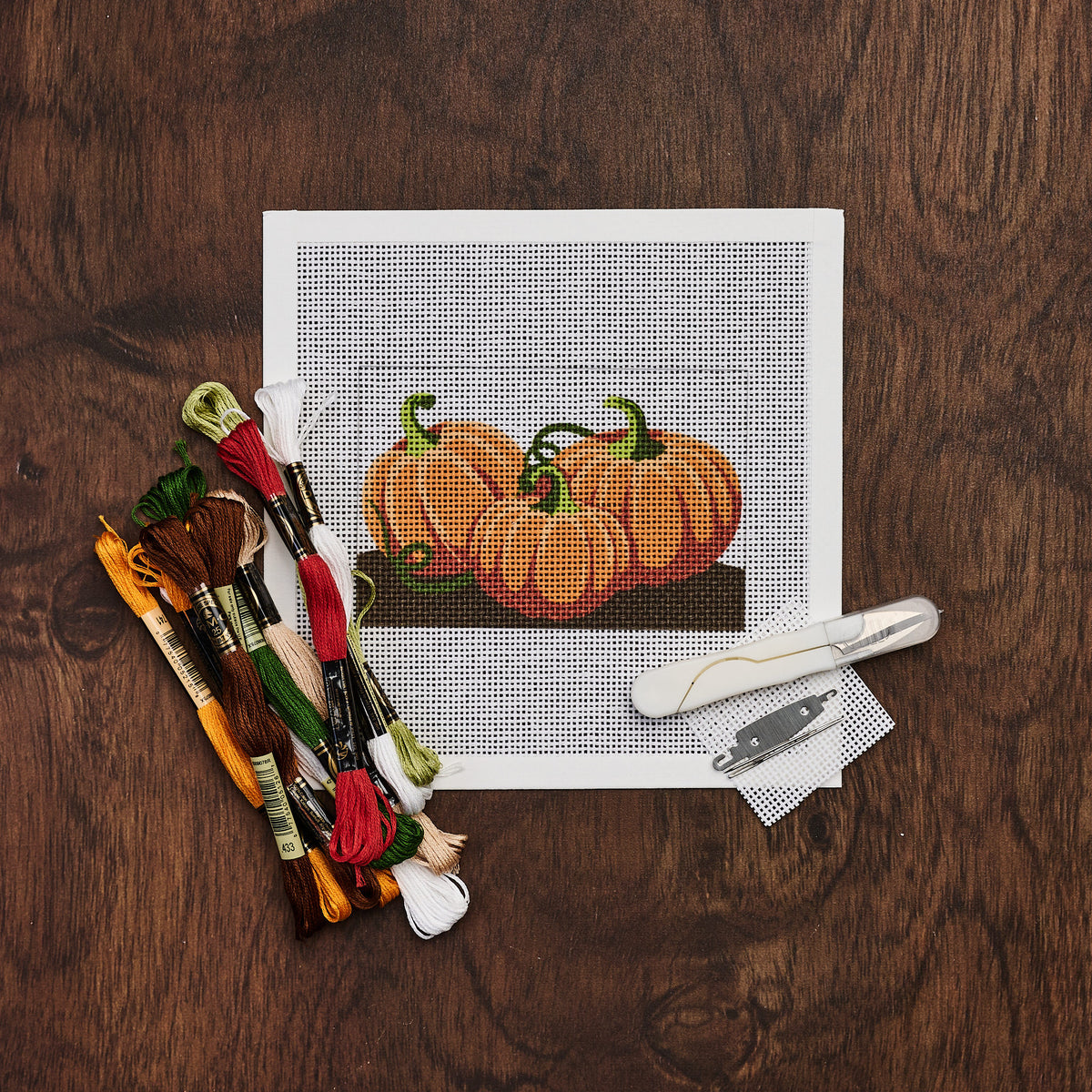 Three Pumpkins Needlepoint Kit on a wood table at Addison West