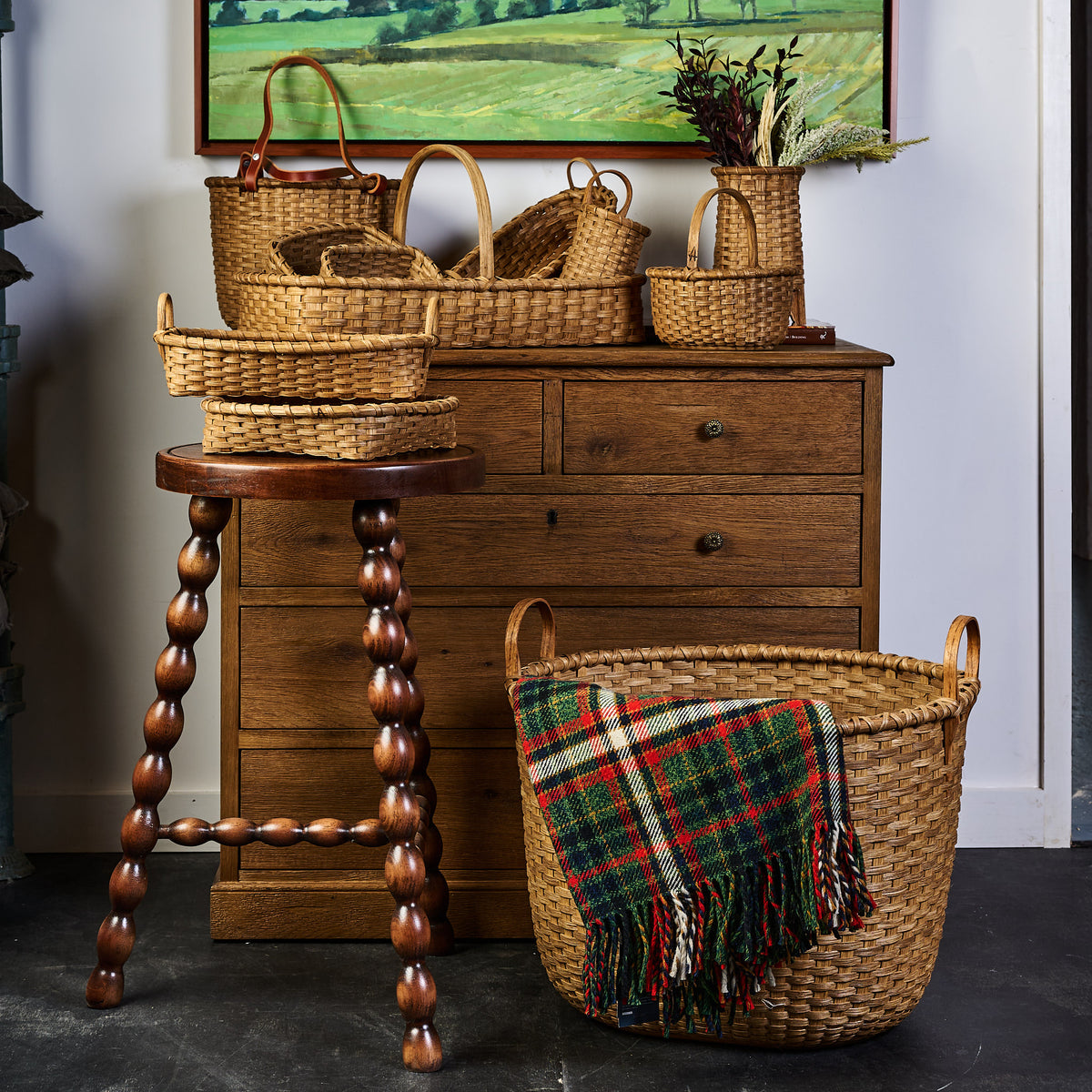 Medium Vermont Laundry Basket next to a dresser styled with many handmade baskets.