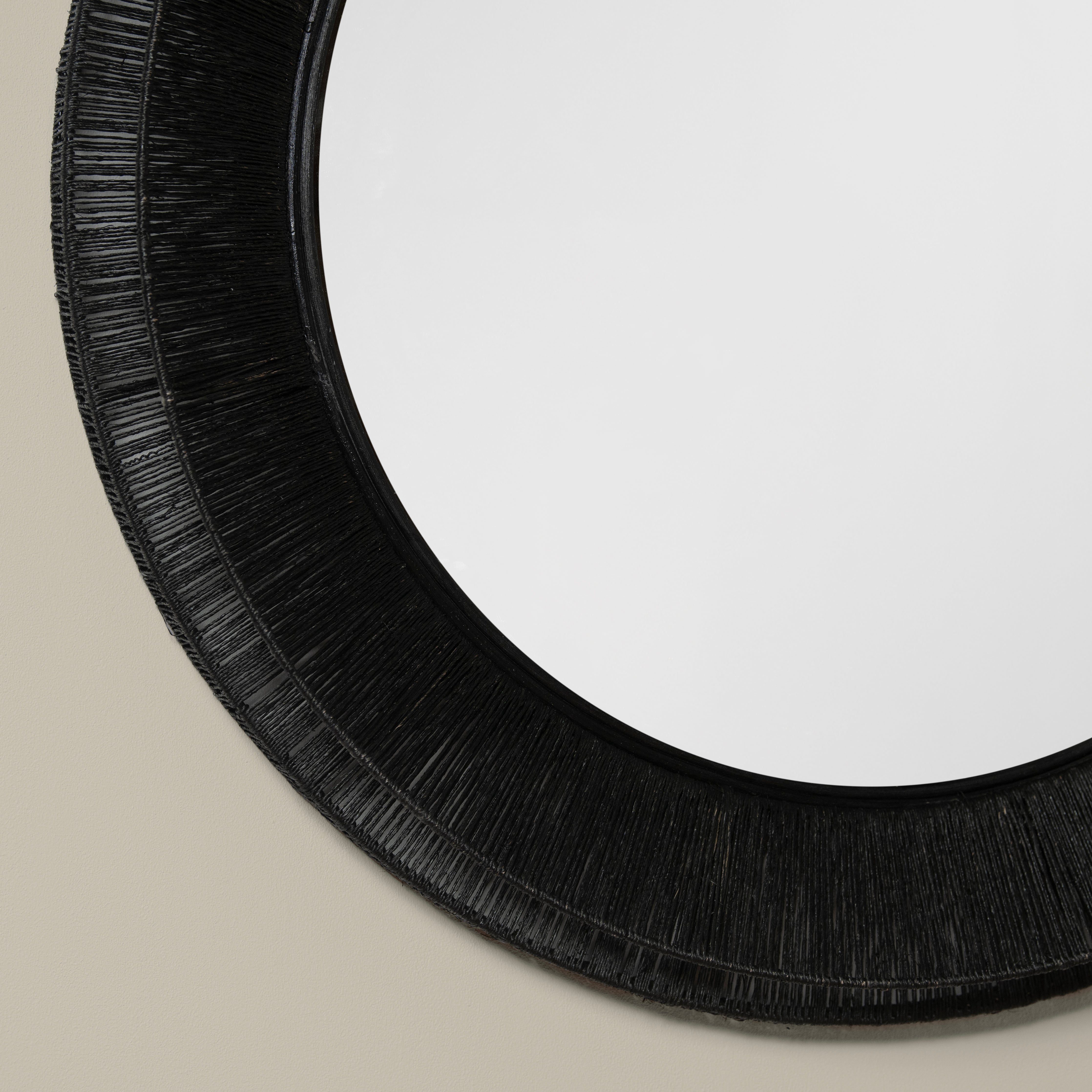 Close up of Collins Large Jute Mirror in Black on a beige wall at Addison West