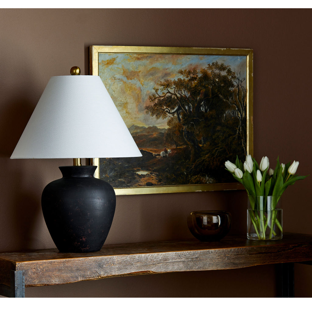 Surya brand black Dalle lamp with flared shade on a wood console with autumnal painting and vase of tulips