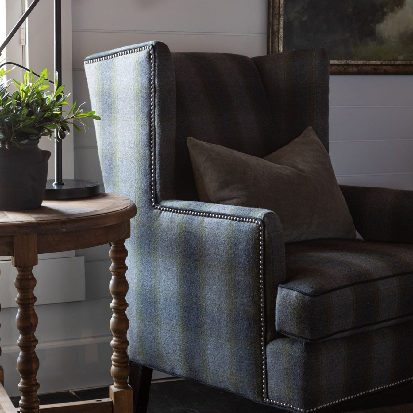 CR Laine Eliot Wingback Chair in Birkdale Moss plaid with muted landscape painting in the background 