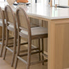 Elle Rounded Caneback Medium Brown Wood with Oatmeal Fabric Counter at a kitchen counter bar area