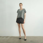 Woman wearing gray Aaron and Amber grey sweater vest and black skirt against a plain background