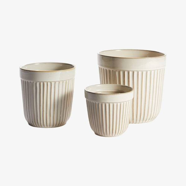 Three cream colored planters with ribbed sides on a white background