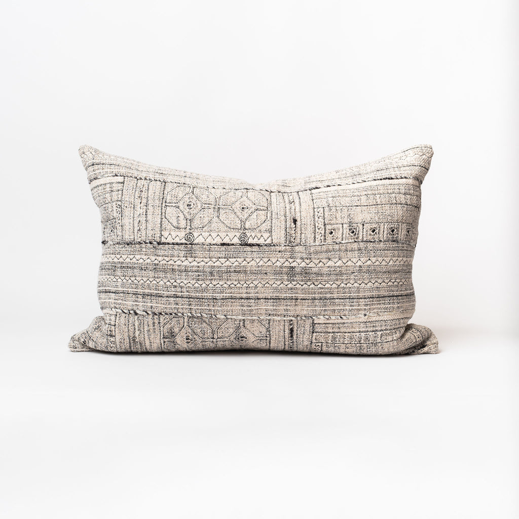 Off white lumbar pillow with textured accents and midnight blue threading on a white background